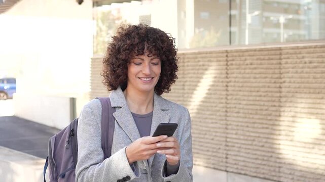 A young woman is engaged in texting on her smartphone while in a vibrant urban setting