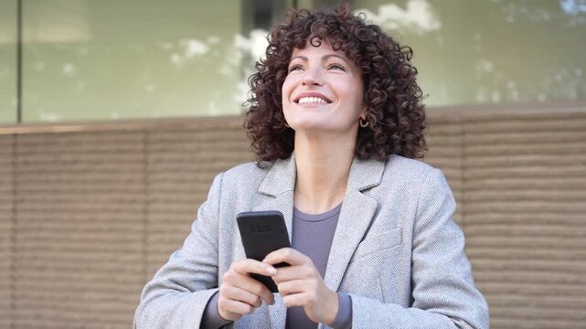 An Excited Woman Celebrating with Her Smartphone Enthusiastically in a Vibrant Urban Setting
