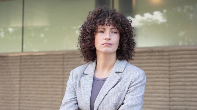 A woman is deeply engaged with her smartphone while outdoors in a vibrant urban setting