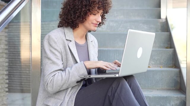 A professional woman engaging in work while using her laptop in an outdoor environment