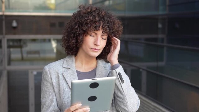 A professional woman uses her tablet in an urban setting, showcasing her business skills