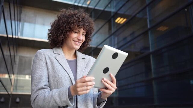 A Professional Woman is Engaged with a Tablet While Outdoors in a Modern Urban Setting