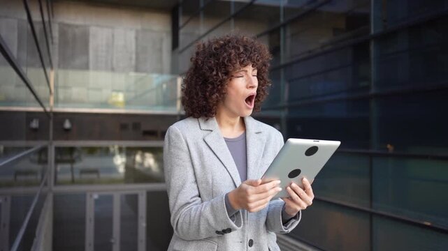 A businesswoman is actively using a tablet while situated in a vibrant modern urban environment