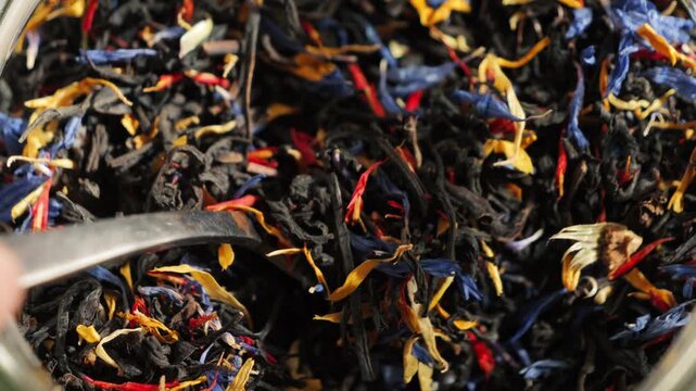 Close-up of loose leaf tea with large tea leaves and flower petals. Aromatic herbal blend, natural ingredients and healthy beverage concept. High quality 4k footage