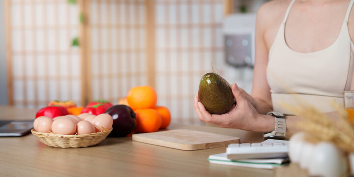 Cropped hands holding fresh avocado on kitchen counter for healthy meal preparation