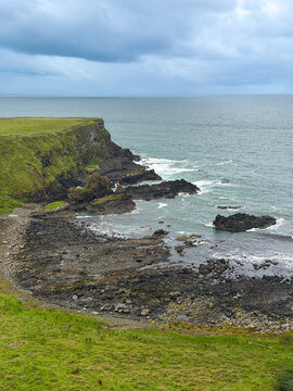 Dark volcanic rocks and grassy cliffs border the North Atlantic beneath stormy clouds along the Causeway Coast near Giant's Causeway, Northern Ireland.