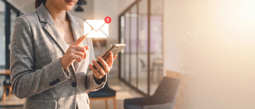 Businesswoman touching glowing email envelope icon with unread notification badge on smartphone, checking new message online. Concept of digital communication, alerts and business correspondence.