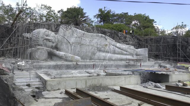 Reclining Buddha statue under construction being carved into a mountain
