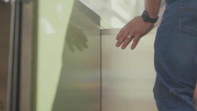 Man's hand rests on stainless steel outdoor kitchen countertop