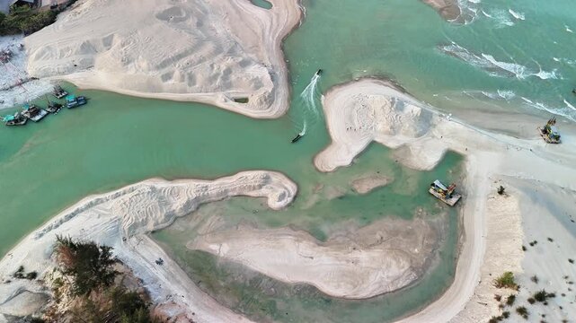 sediment filled estuary mouth with changing coastal morphology, sand deposits and maritime engineering activities near shoreline area