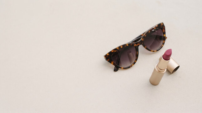 Sunglasses and lipstick on a neutral background, beauty and fashion flat lay