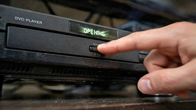 Person pressing eject button on dvd player