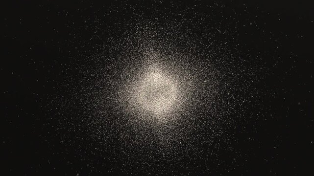 Emerging bright particle cloud forming expanding ring in dark void, with central point and halo