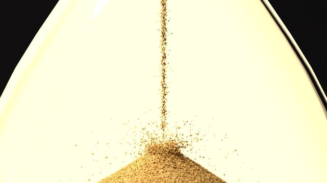 Streaming golden sand forming conical pile in lower bulb after hourglass flip, measuring time