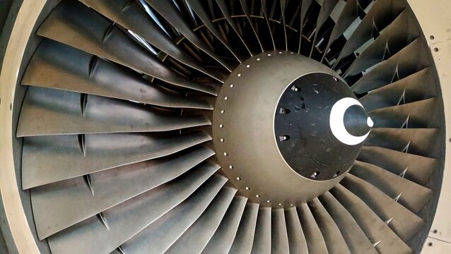 Close-up of an aircraft turbofan engine showing the front fan blades and spinner cone. Industrial aviation background emphasizing engineering, technology, and aerodynamics
