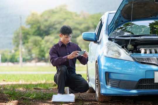 Insurance agent taking photo of broken down blue car for claim report