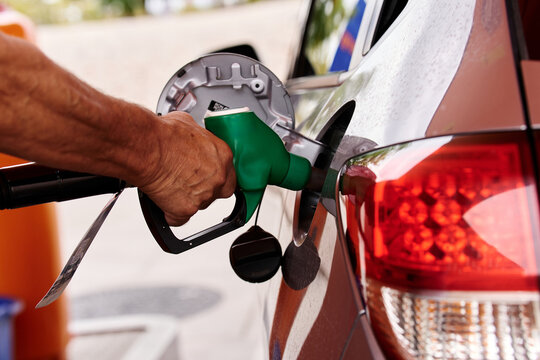 Hand refueling car at gas station with rising fuel prices
