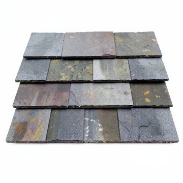 Layered slate roof shingles on white background showing texture and natural color variations in roofing materials