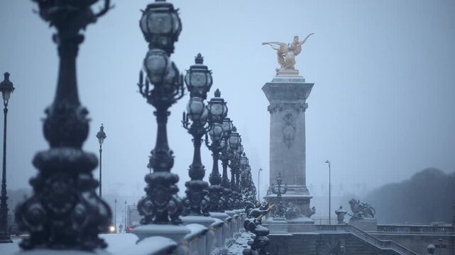 Snow-covered Alexandre III bridge in Paris during winter snowfall, with ornate street lamps and golden statues creating a picturesque and atmospheric cityscape