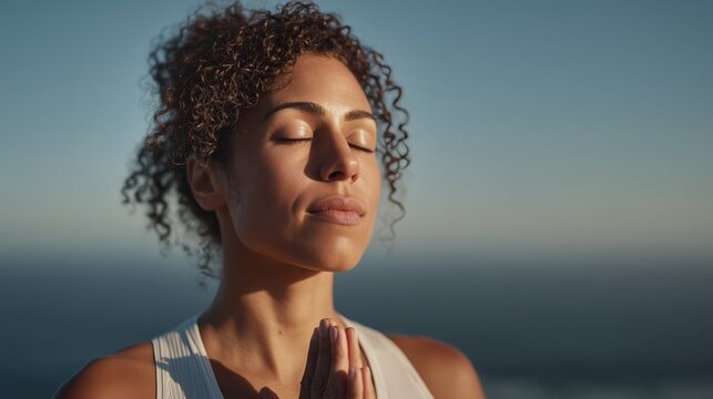 A woman meditates with her eyes closed during an outdoor yoga practice.