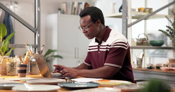 Pottery, business and man with laptop, typing and sales review for inventory management. Studio, startup and black person on computer for online order, checklist or stock for ceramic product at store