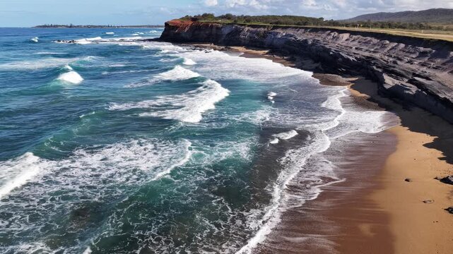 Aerial video flying over the rugged coastline at Lake Arragan, featuring sandy shoreline, rocky formations and waves rolling in from the Pacific Ocean