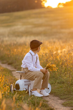 Sweet preteen child, boy, playing in a field on sunset with kite and old vingate car, walking with grandmother in the countryside