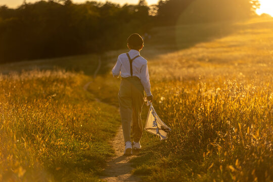Sweet preteen child, boy, playing in a field on sunset with kite and old vingate car, walking with grandmother in the countryside