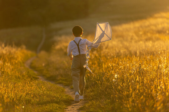 Sweet preteen child, boy, playing in a field on sunset with kite and old vingate car, walking with grandmother in the countryside
