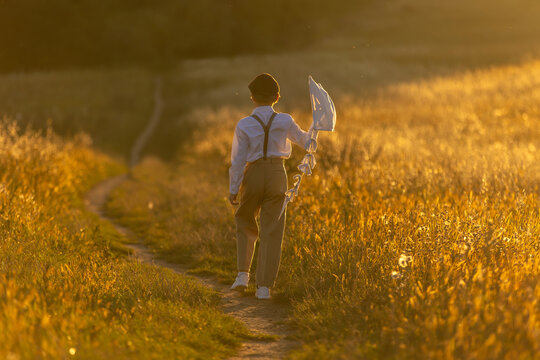 Sweet preteen child, boy, playing in a field on sunset with kite and old vingate car, walking with grandmother in the countryside