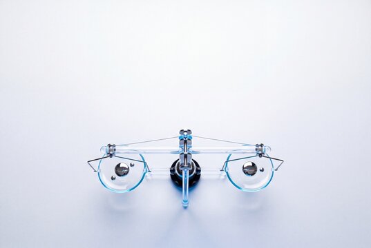Top view of a modern transparent glass balance scale with metal weights balanced equally on a white background with copy space