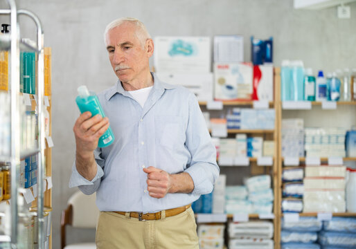 Elderly man chooses shampoo shower gel at pharmacy
