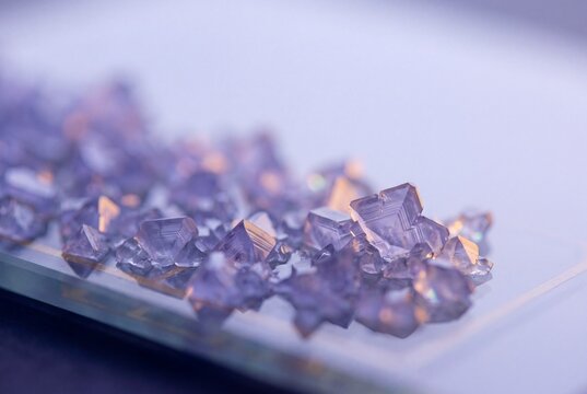 Macro photograph of translucent purple crystals with geometric hopper structures grown in a laboratory setting