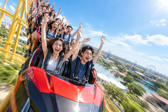 Roller coaster train descending a steep drop with joyful passengers, motion blur.