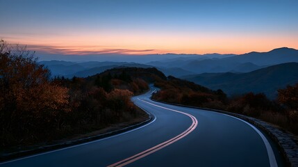 Obraz premium Curving mountain highway at dusk with soft sunset colors and distant blue mountain silhouettes