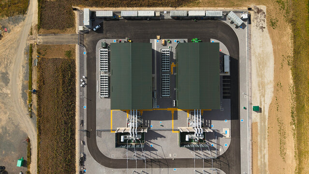 Aerial view of synchronous condensers at a National Grid electrical substation with two industrial buildings, cooling fans, and electrical infrastructure in Walpole, England, United Kingdom.