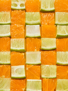 Grid pattern of orange and lime citrus fruit cubes close up