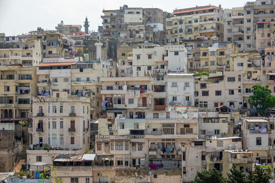 Densely packed apartment buildings climb a hillside beneath a mosque minaret, North Governorate, Tripoli, Lebanon