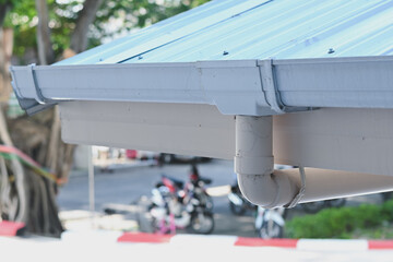 White plastic rain gutter system installed on building roof. © Aphisith