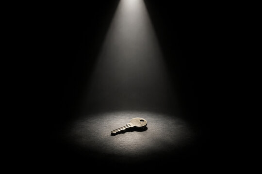 Spotlight on a solitary key on dark stage, high contrast with dramatic shadows.
