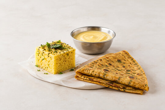 Steamed dhokla square with thepla flatbread and chickpea batter bowl, retail food display