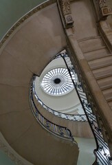 Obraz premium Looking up of the Nelson Staircase within Somerset House in London, a grand spiral staircase inside a neoclassical building, featuring a prominent circular oculus (skylight) at the top and the intrica