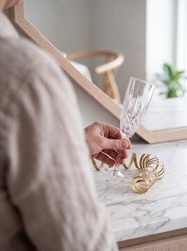Man Holding an Empty Crystal Champagne Flute next to Gold Festive Ribbon on Marble Countertop