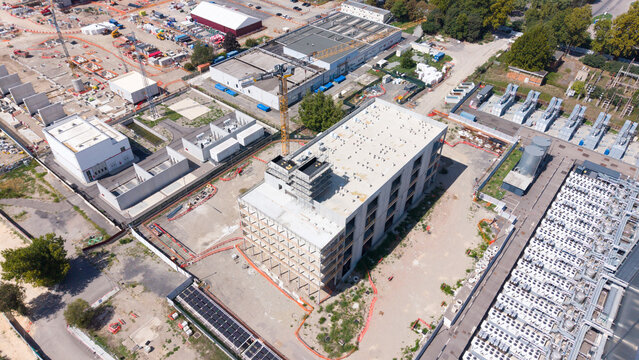 Aerial view of the Equinix MLSS1 data center construction site with a tall crane, surrounding industrial buildings, and cooling infrastructure in Castelletto, Lombardia, Italy.