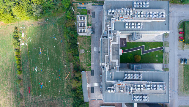 Aerial view of an internet service provider facility featuring rooftop HVAC units and an adjacent outdoor dog training area with agility equipment in Milan, Lombardy, Italy.