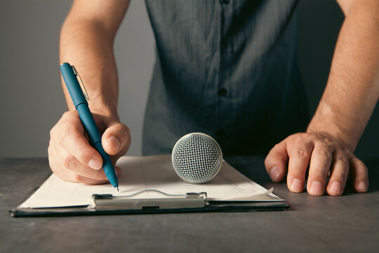 Man holding a microphone in his hand. On a gray background.