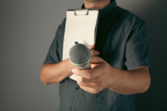 Man holding a microphone in his hand. On a gray background.