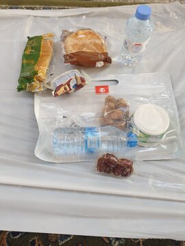 Madinah, Saudi Arabia - March 7, 2025 : View of bread, dates, yogurt, bottled water, and packaged snacks served for breaking the fast during Ramadan at Masjid Nabawi with blurred background.