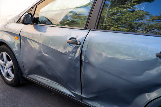 Close-up of severely dented car doors showing body damage caused by a road accident.