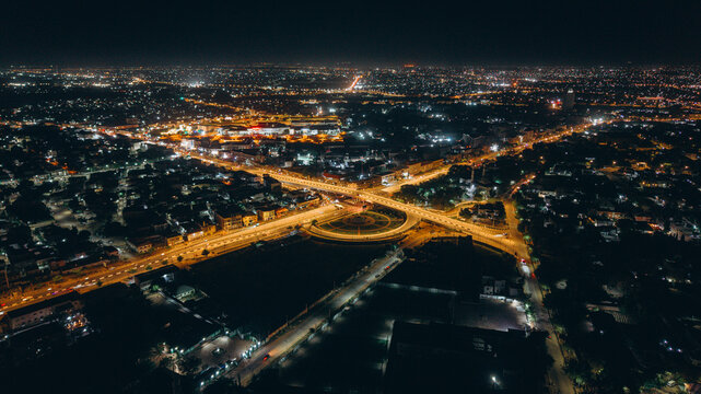 Aerial view of the illuminated cityscape of Kano at night, featuring a prominent roundabout and glowing street lights stretching across the urban landscape in Kano, Kano, Nigeria.
